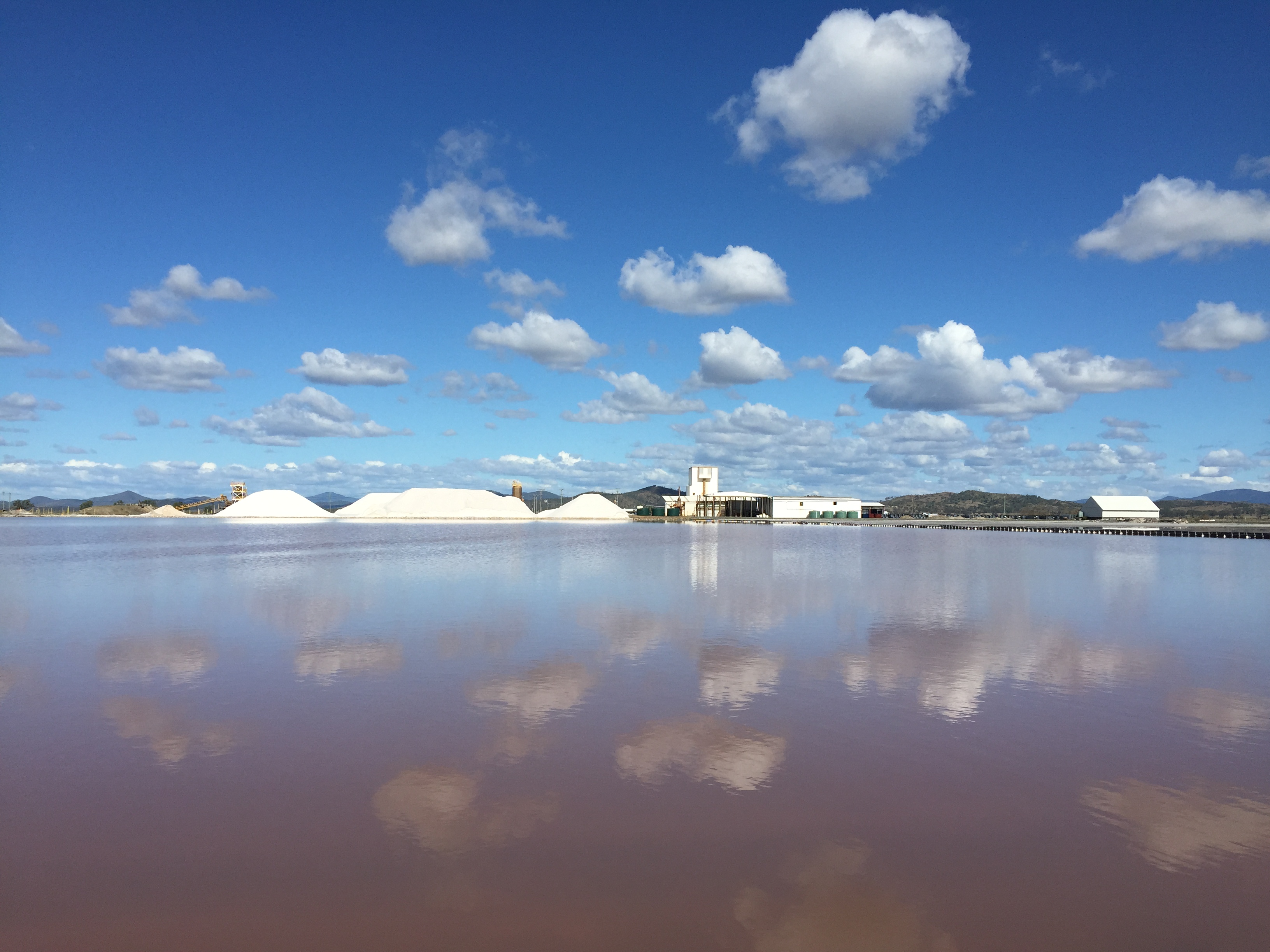 An image of a salt mine. Clouds are reflected in the water in the scenic photo.