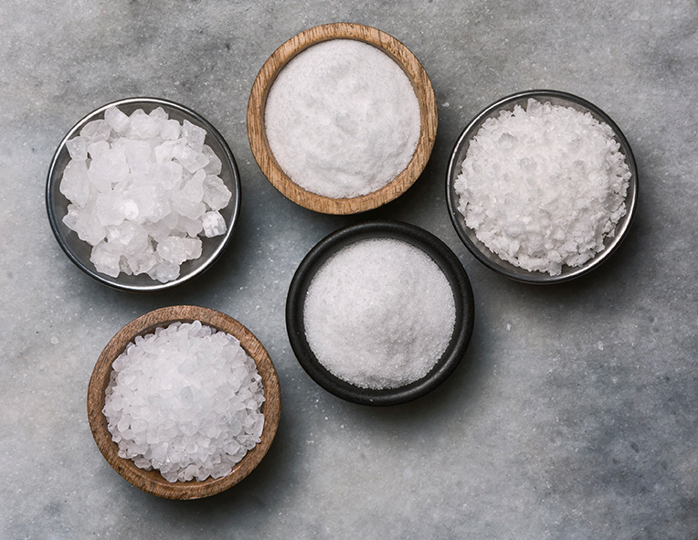 A photo of five bowls of salts ranging from superfine to coarse 
